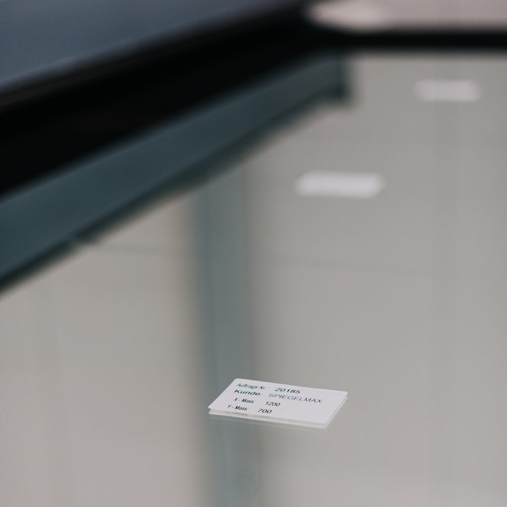 Spiegelglas auf dem Schneidtisch mit Auftragslabel – millimetergenaue Maßfertigung bei Spiegelmax