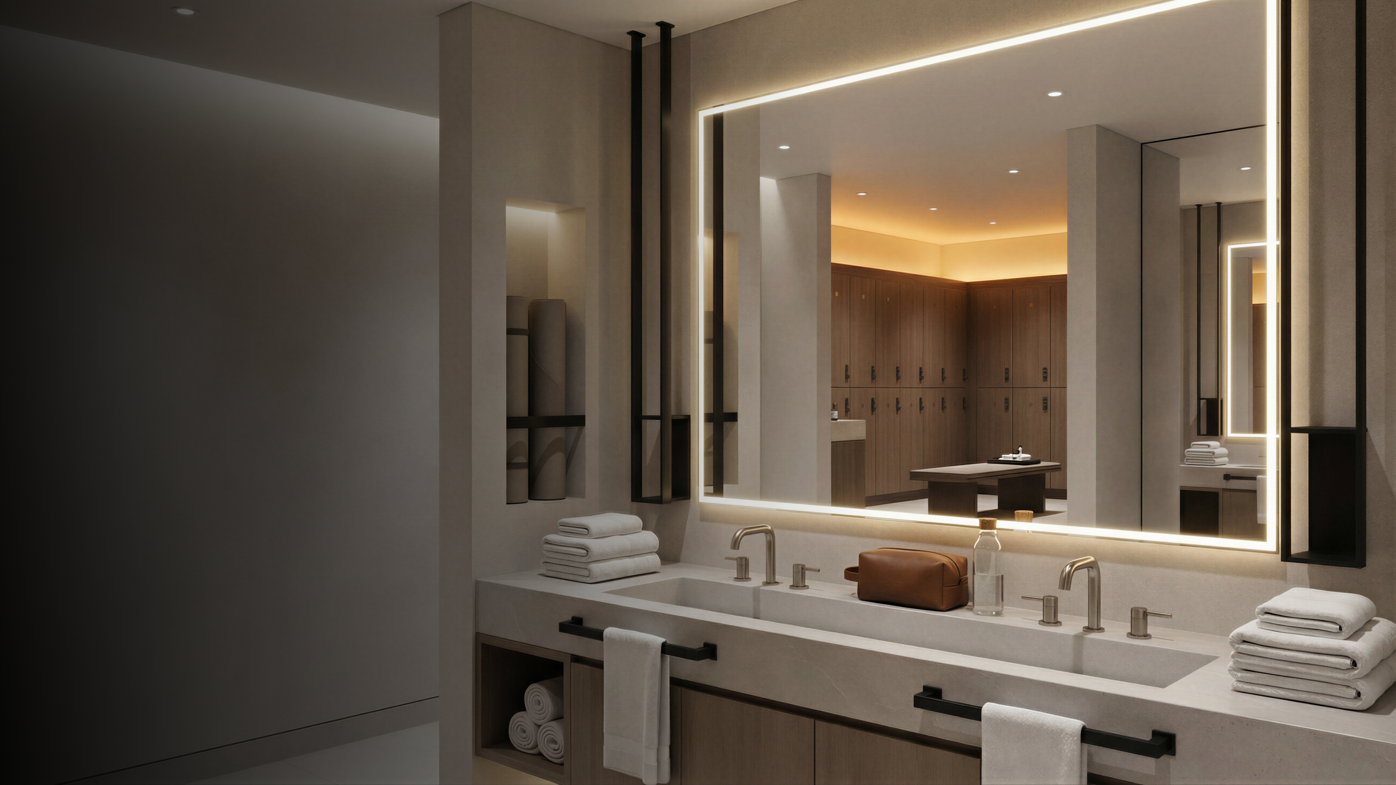 Großer beleuchteter Badspiegel mit LED-Rahmen über einem steinernen Doppelwaschtisch. Im Hintergrund ein Spa-Bereich mit Holzfächern und Liege.
