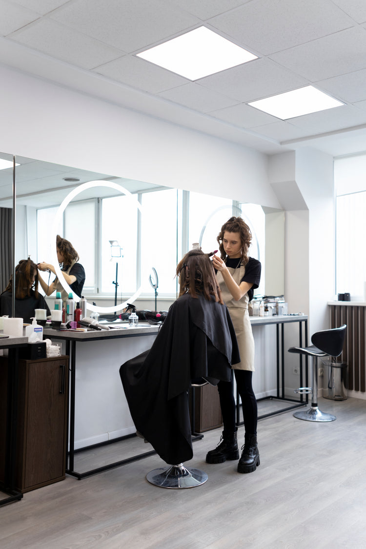 Moderner Friseursalon mit großem Spiegel, LED-Ringlicht und professionellem Stylingplatz während einer Haarbehandlung