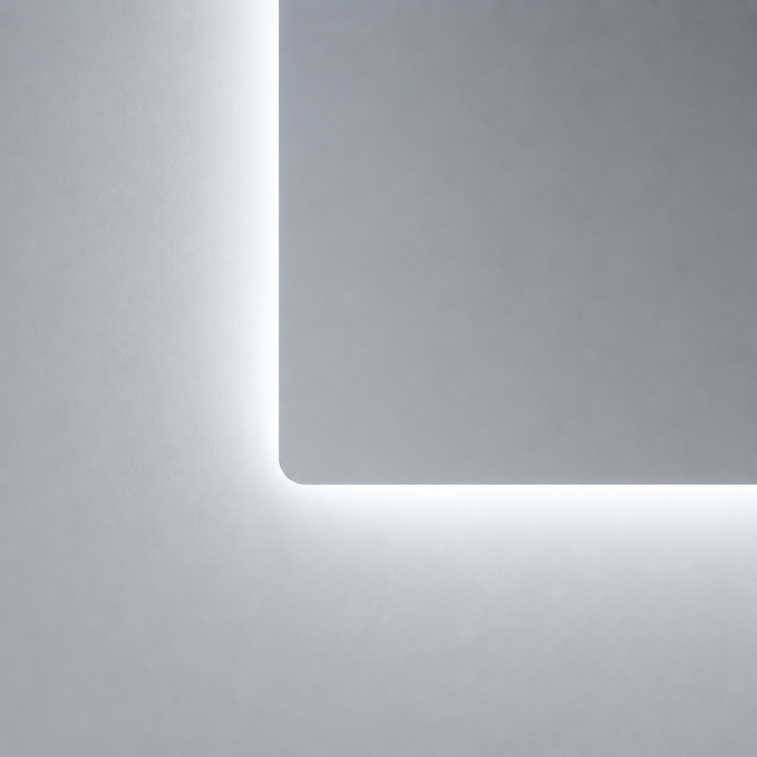 Kaltweißer LED-Badspiegel mit abgerundeter Ecke und indirekter Beleuchtung an heller Badezimmerwand.