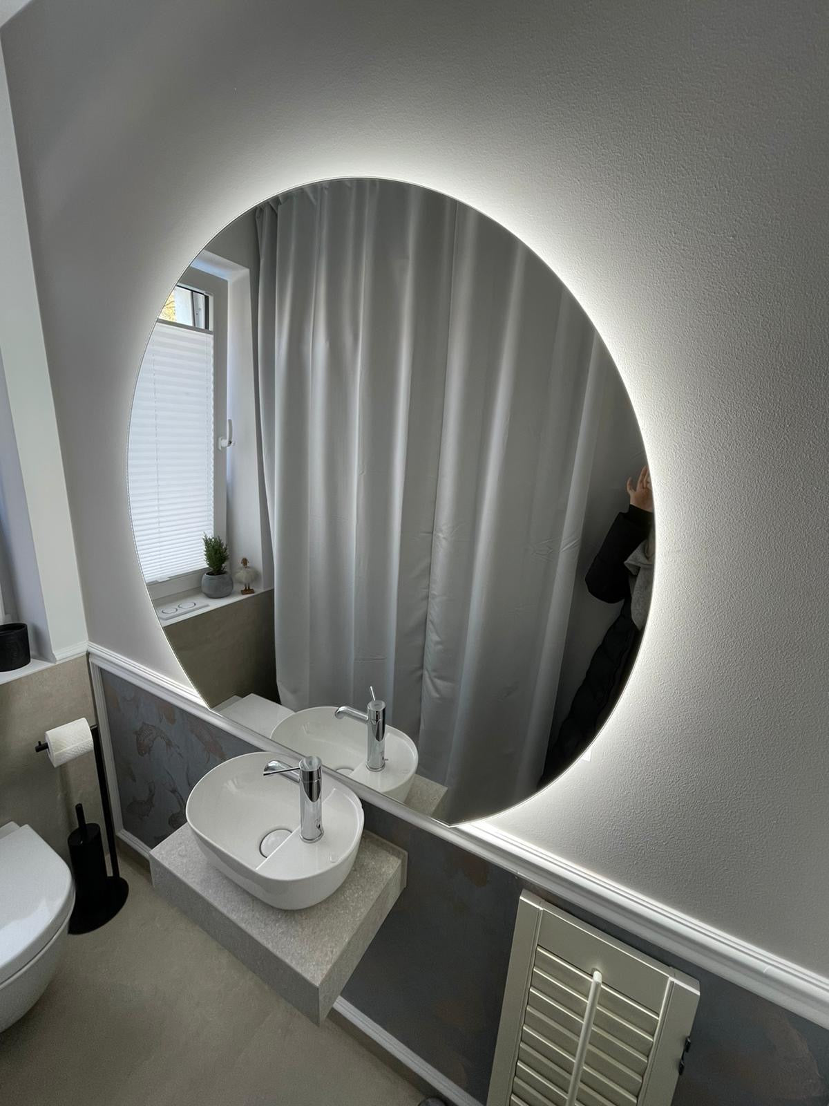 Runder LED-belesener Badspiegel über kleinem Waschbecken im modernen Gäste-WC.