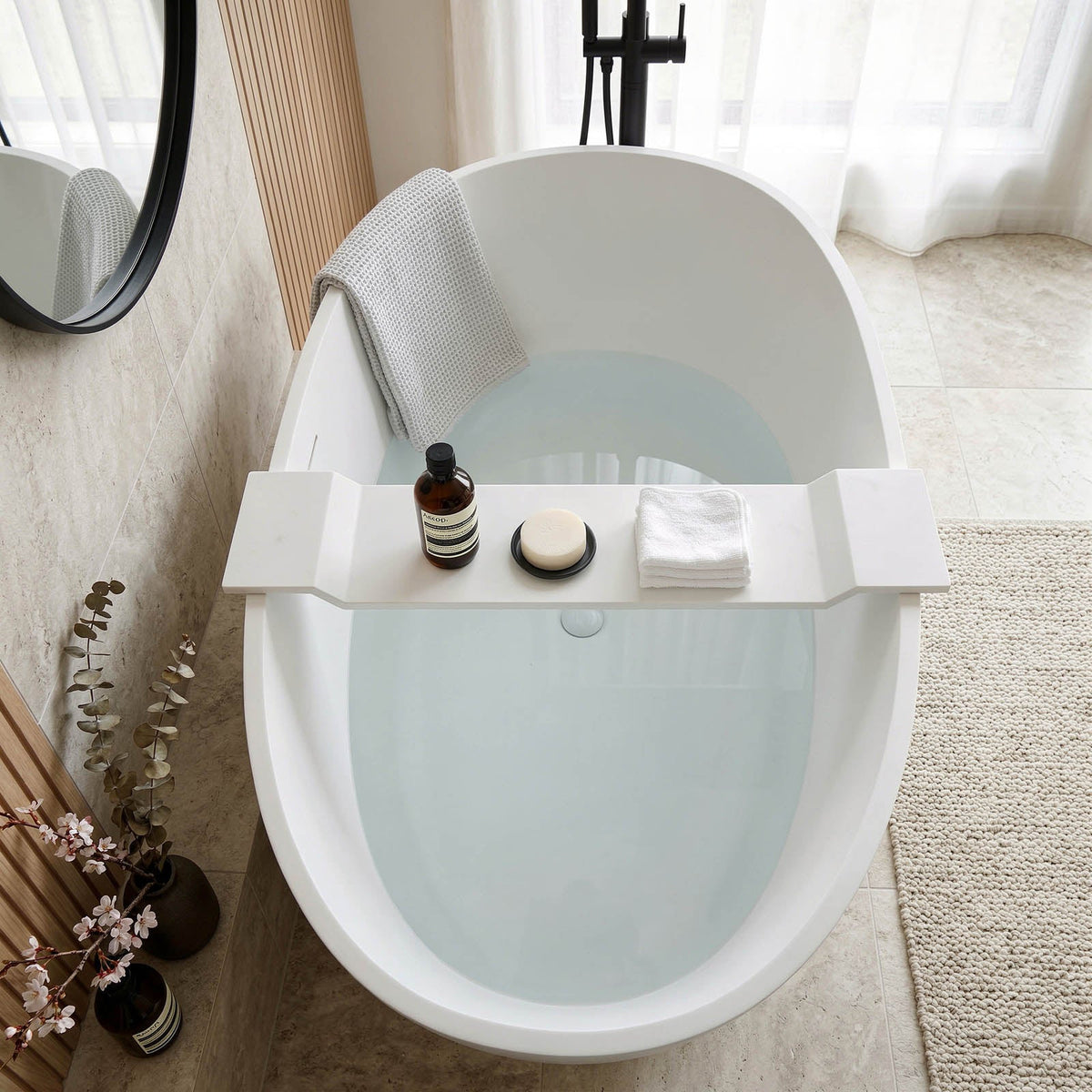 Matte weiße Wannenablage aus Mineralguss, quer über der Badewanne mit Pflegeprodukten